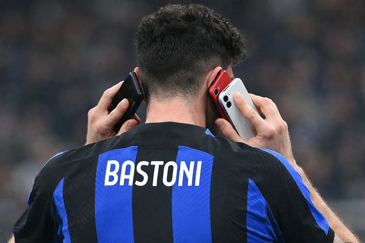 Bastoni, difensore dell'Inter, con tre telefoni alle orecchie